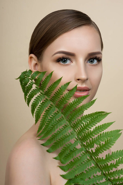 Young beautiful smiling model with natural make up, Long eyelashes and green leaf of fern. Spa, skincare and wellness. Beauty and skin care concept. - Fotografie, Obrázek