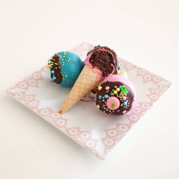Close up image of assorted colorful cupcakes in ice cream cones on a plate - Zdjęcie, obraz