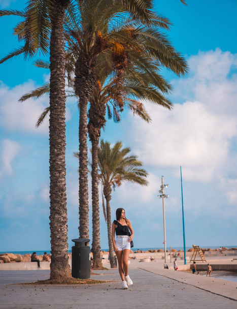 Summer lifestyle, brunette Caucasian with white shorts and black t-shirt on the Mediterranean coast - Fotoğraf, Görsel