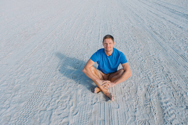 Un tipo caminando por la playa vacía de Miami. Feliz hombre guapo turista en ropa casual sentado en la playa de arena. Concepto de viajes y turismo. - Foto, Imagen