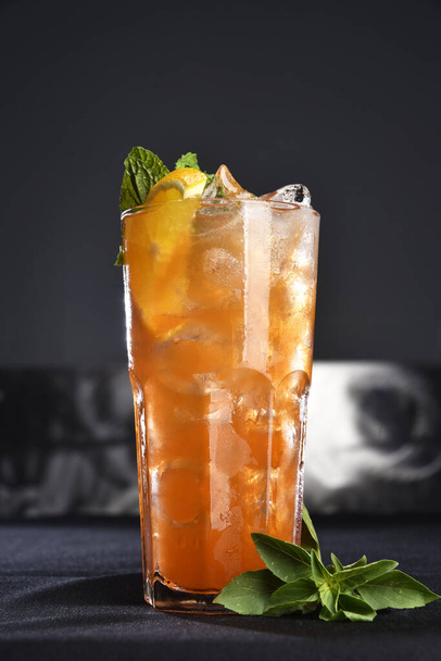 освежающий алкогольный напиток с ягодами, водкой со льдом и джином, лимонная кожура подается в стеклянной чашке на прилавке на размытом фоне - Фото, изображение