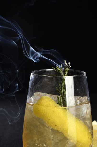 bevanda alcolica rinfrescante con bacche, vodka di ghiaccio e gin, scorza di limone servita in tazza di vetro sul bancone su sfondo sfocato - Foto, immagini