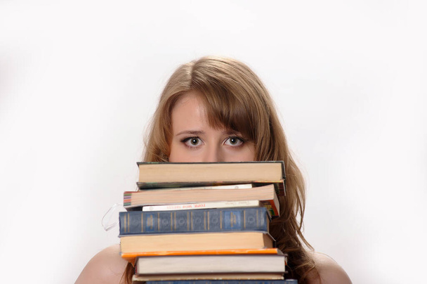 beautiful blonde student in the studio among the many books - Fotografie, Obrázek
