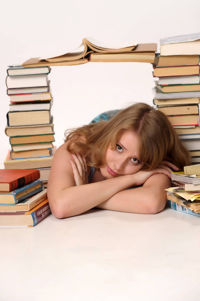 beautiful blonde student in the studio among the many books - Fotografie, Obrázek
