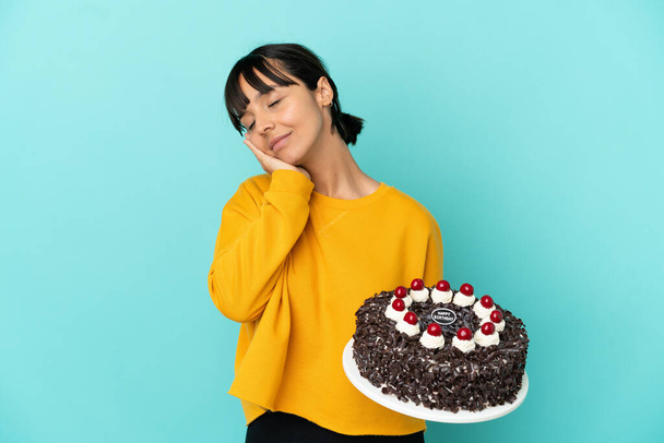 Young mixed race woman holding birthday cake making sleep gesture in dorable expression - Foto, immagini