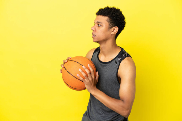 Afroamerikaner auf gelbem Hintergrund beim Basketballspielen isoliert - Foto, Bild