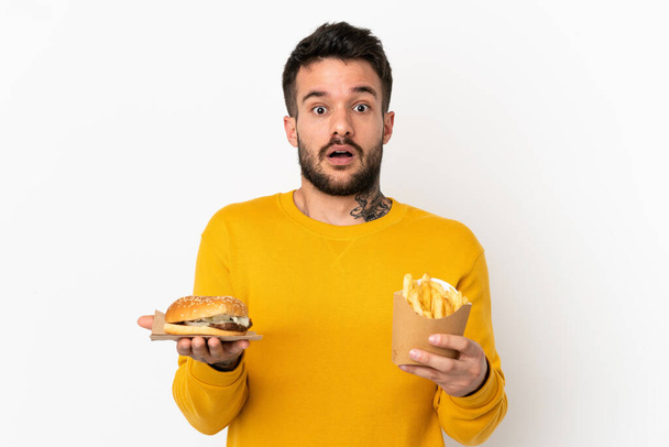 drží smažené hranolky a cheeseburger na izolovaném pozadí - Fotografie, Obrázek