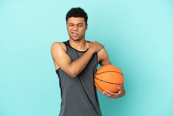 Basketball player African American man isolated on blue background suffering from pain in shoulder for having made an effort - Photo, Image