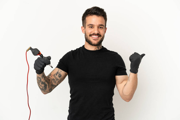 Tatoueur homme sur fond blanc isolé pointant vers le côté pour présenter un produit - Photo, image