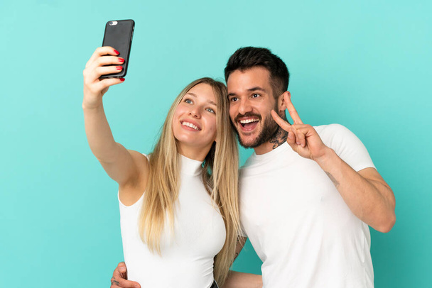 Nuori pari yli eristetty sininen tausta tehdä selfie mobiili - Valokuva, kuva