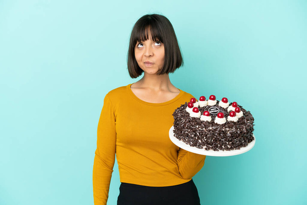 Young mixed race woman holding birthday cake and looking up - Foto, Bild