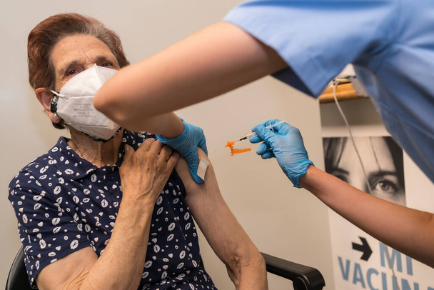 San Sebastian, Gipuzkoa. Spain. May 8, 2021: A scared elderly woman receiving the dose prick by a young nurse at the vaccination center, covid-19. Coronavirus - Foto, Imagen