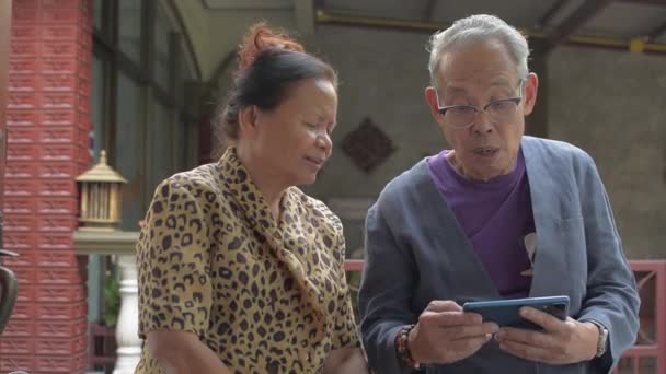 Asyalı mutlu sevimli kız, evdeki cep telefonundan sosyal video veya film izlerken yaşlı büyükbabasına katılıyor. Aile bağları.  - Video, Çekim