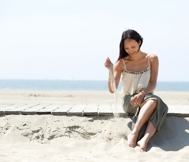 žena sedí u pláže s pískem v ruce - Fotografie, Obrázek