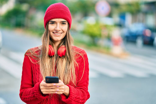 Młoda Latynoska kobieta korzystająca ze smartfona i słuchawek w mieście. - Zdjęcie, obraz