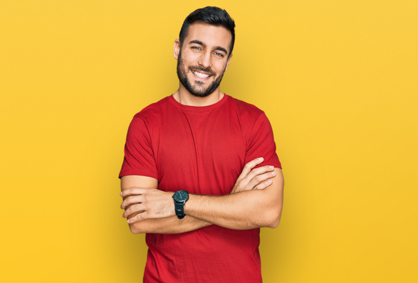 Jonge Spaanse man in casual kleding vrolijk gezicht glimlachend met gekruiste armen kijkend naar de camera. positieve persoon.  - Foto, afbeelding