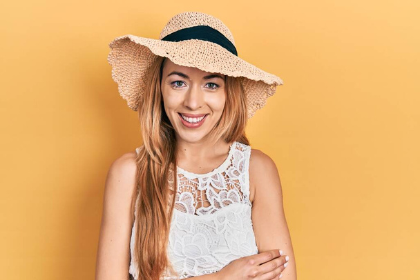 Yazlık şapkalı, mutlu yüzlü, kollarını kavuşturup kameraya bakan beyaz bir kadın. pozitif kişi.  - Fotoğraf, Görsel