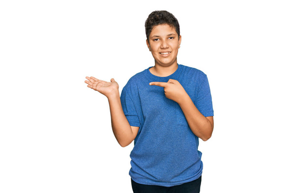 Tinédzser spanyol fiú visel alkalmi ruhák elképedt és mosolyog a kamera, miközben bemutatja a kezét, és ujjal mutogatott.  - Fotó, kép