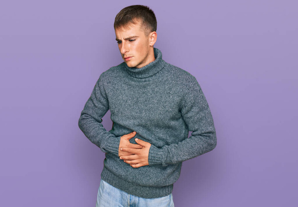 Young blond man wearing casual clothes with hand on stomach because indigestion, painful illness feeling unwell. ache concept.  - Photo, Image