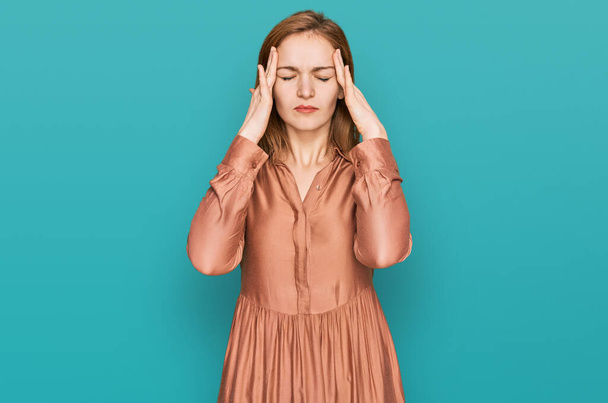 Junge kaukasische Frau in sexy Partykleid, die unter Kopfschmerzen leidet verzweifelt und gestresst, weil Schmerzen und Migräne. Hände auf den Kopf.  - Foto, Bild