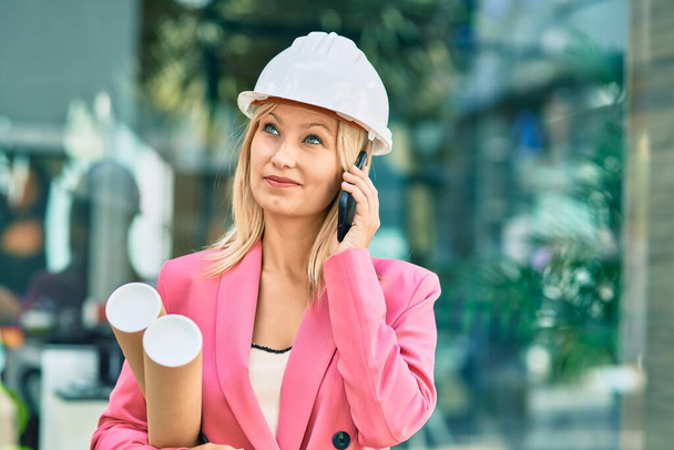 Young caucasian architect woman smiling happy using smartphone at the city - Photo, Image