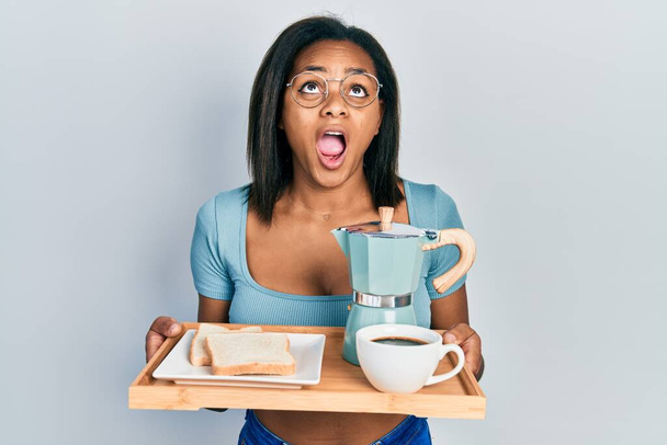 Nuori afrikkalainen amerikkalainen tyttö tilalla tarjotin aamiaisella ruokaa vihainen ja hullu huutaa turhautunut ja raivoissaan, huutaen vihaa katselee ylös.  - Valokuva, kuva