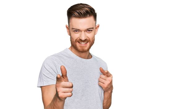 Homem ruivo jovem vestindo casual cinza t-shirt apontando os dedos para a câmera com rosto feliz e engraçado. boa energia e vibrações.  - Foto, Imagem