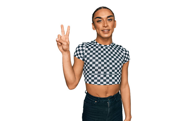 Hispanic transgender man wearing make up and long hair wearing modern clothes showing and pointing up with fingers number two while smiling confident and happy.  - Foto, immagini