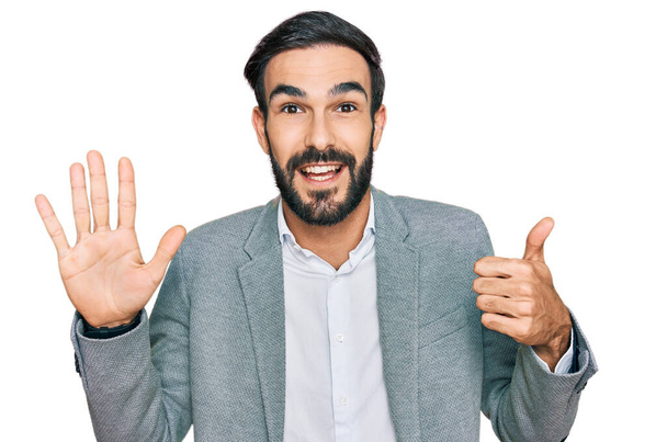 Giovane uomo ispanico che indossa abiti da lavoro mostrando e indicando con le dita il numero sei mentre sorride fiducioso e felice.  - Foto, immagini