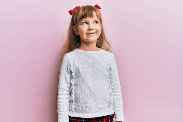 Petite fille caucasienne enfant portant des vêtements décontractés regardant vers le côté, pose de profil relax avec visage naturel et sourire confiant.  - Photo, image