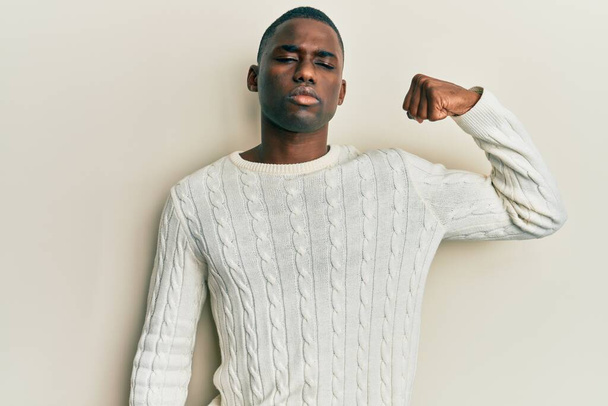 Nuori afrikkalainen amerikkalainen mies päällään rento vaatteita vahva henkilö osoittaa käsivarren lihas, luottavainen ja ylpeä vallasta  - Valokuva, kuva
