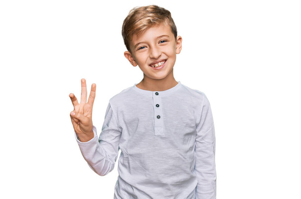 Petit garçon caucasien enfant portant des vêtements décontractés montrant et pointant vers le haut avec les doigts numéro trois tout en souriant confiant et heureux.  - Photo, image