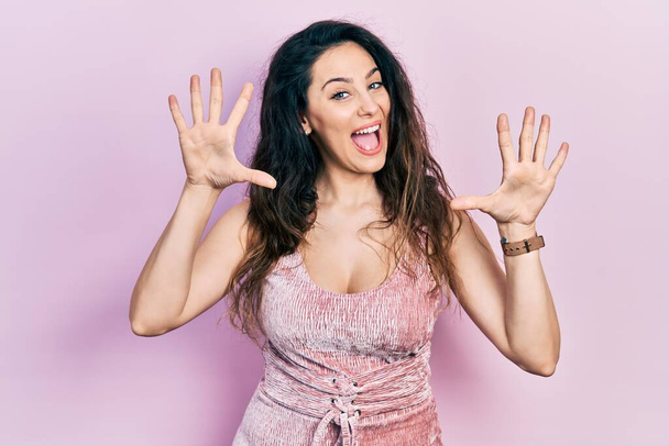 Young hispanic woman wearing casual clothes showing and pointing up with fingers number ten while smiling confident and happy.  - Photo, Image