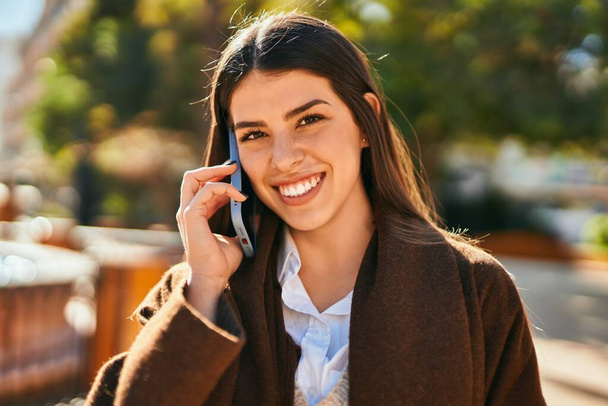 Jeune femme hispanique souriant heureux parler sur le smartphone à la ville. - Photo, image