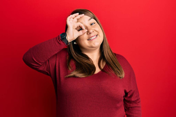 Beautiful brunette plus size woman wearing casual clothes smiling happy doing ok sign with hand on eye looking through fingers  - Fotoğraf, Görsel