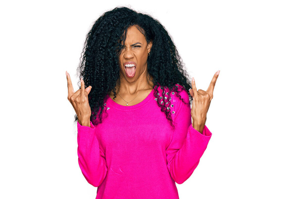 Middle age african american woman wearing casual clothes shouting with crazy expression doing rock symbol with hands up. music star. heavy concept.  - Valokuva, kuva