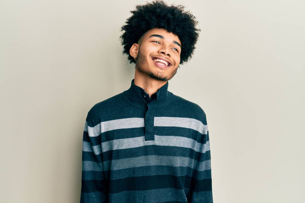 顔に笑みを浮かべて横に離れて見てカジュアルな服を着てアフロの髪を持つ若いアフリカ系アメリカ人の男性は、自然な表情。自信を持って.  - 写真・画像
