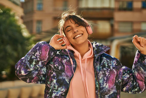 Jeune femme sportive hispanique souriant heureux en utilisant des écouteurs dansant à la ville. - Photo, image