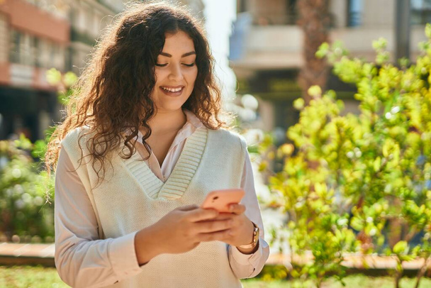 Young hispanic woman smiling happy using smartphone at the city. - Foto, Bild