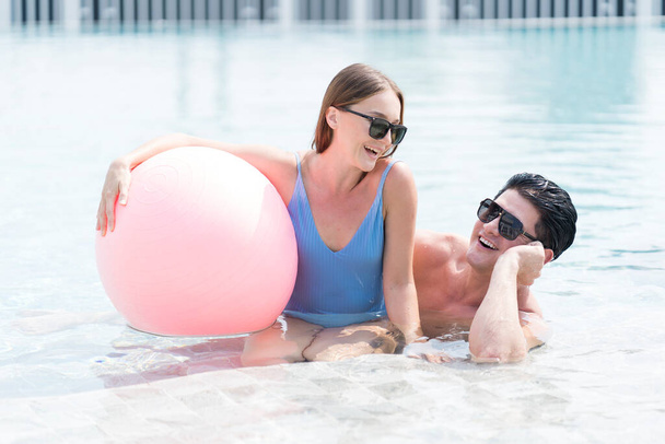 Щасливий чоловік і жінка грають у басейні з пляжним м'ячем. У пари ванна в курортному басейні
.  - Фото, зображення