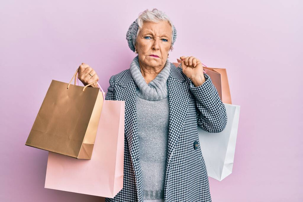 Mujer mayor de cabello gris sosteniendo bolsas de compras deprimida y preocupada por la angustia, llorando enojada y asustada. expresión triste.  - Foto, Imagen