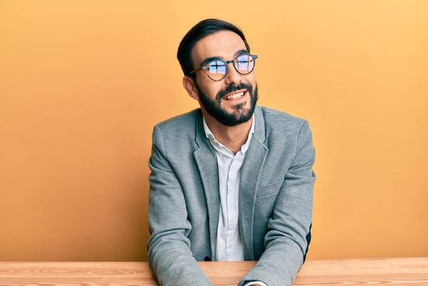 Jeune homme hispanique travaillant au bureau regardant de côté avec le sourire sur le visage, expression naturelle. riant confiant.  - Photo, image