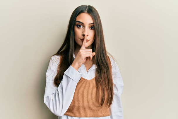 Beautiful brunette young woman wearing casual clothes asking to be quiet with finger on lips. silence and secret concept.  - Foto, imagen