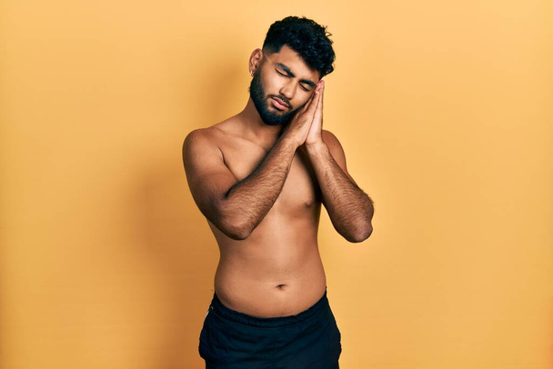 Arab man with beard wearing swimwear shirtless sleeping tired dreaming and posing with hands together while smiling with closed eyes.  - Photo, Image