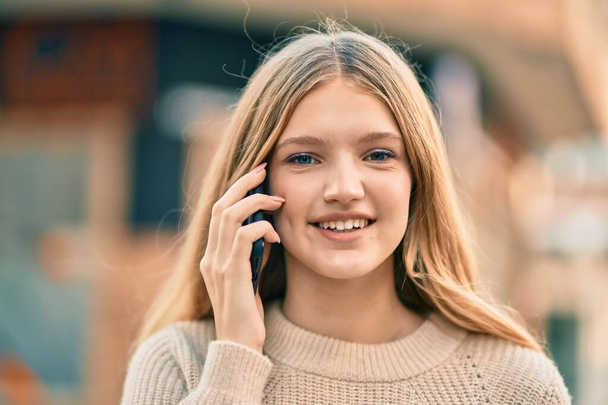 Beautiful caucasian teenager smiling happy talking on the smartphone at the city. - Photo, Image