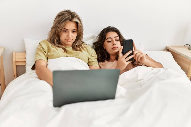 Junges Paar nutzt Smartphone und schaut Film im Schlafzimmer - Foto, Bild