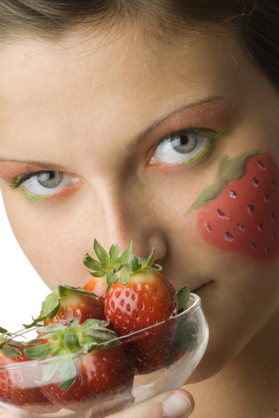 portrait of a young and cute brunette with big strawberry painted on her face and colored eyes - Foto, imagen