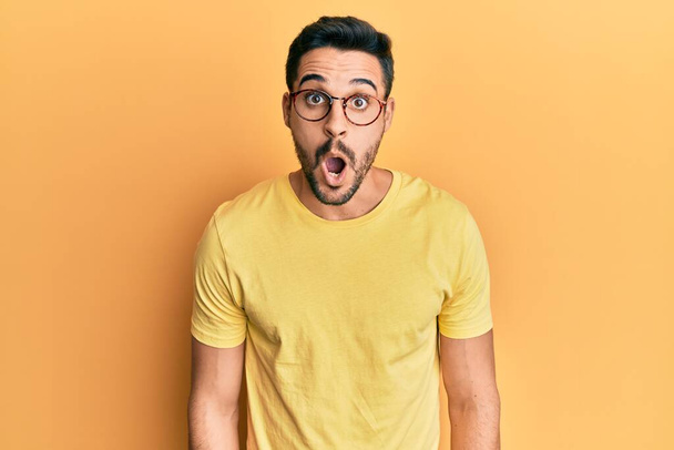 Young hispanic man wearing casual clothes and glasses afraid and shocked with surprise expression, fear and excited face.  - Photo, Image