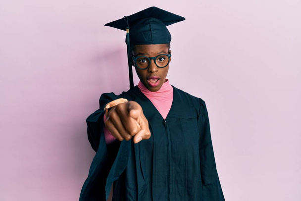 Young african american girl wearing graduation cap and ceremony robe pointing displeased and frustrated to the camera, angry and furious with you  - Valokuva, kuva