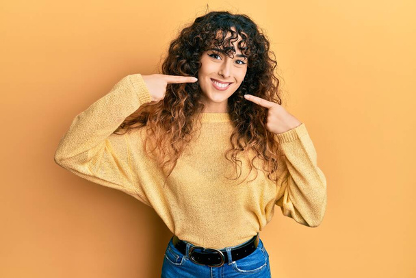 Young hispanic girl wearing casual clothes smiling cheerful showing and pointing with fingers teeth and mouth. dental health concept.  - Fotoğraf, Görsel